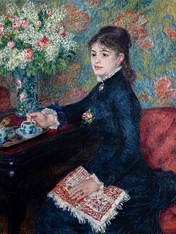 Woman in a dark dress sitting at a piano with flowers and a cup in the background